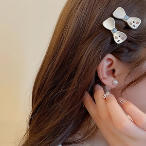 Détail d'une pince à cheveux en forme de nœud avec perles et strass sur modèle