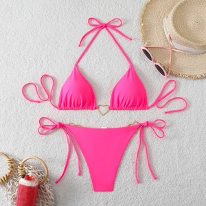 Detailed flat lay of pink bikini set with golden heart rings and summer beach accessories