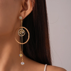 Detail of boho gold tassel earrings with straw hoop and crystal star moon charms