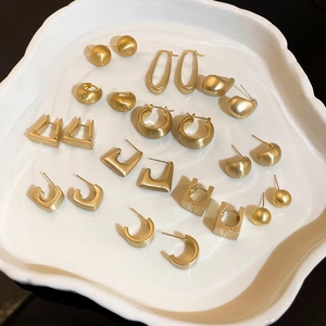 Nahaufnahme goldener geometrischer Ohrstecker auf einem weißen Keramiktablett