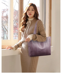Side view of a large deep purple PU leather tote bag worn by a model in soft daylight
