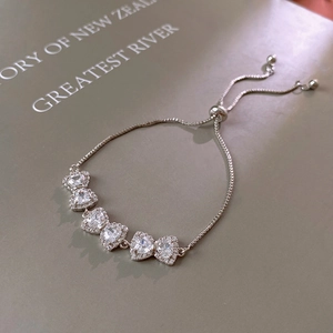 Macro shot of silver adjustable bracelet with five heart-shaped zircons and halo settings