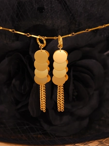 Détail de boucles d'oreilles dorées à disques et franges sur tissu de roses noires