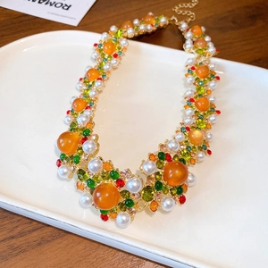 Detailed close-up of retro baroque necklace with colorful crystals and pearls in white tray