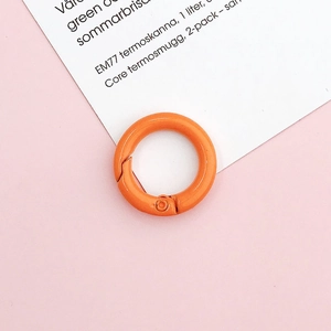 Detail shot of a bright orange 20mm round spring gate ring hook on a pink background