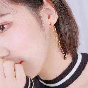 Gros plan de boucles d'oreilles pendantes dorées avec arcs ondulés sur un mannequin