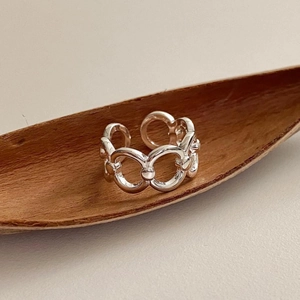 Macro detail of sterling silver chain link ring on natural textured wood tray