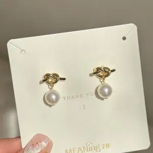 Elegant gold knot pearl earrings on a display card for a minimalist everyday jewelry look