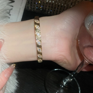 Vue détaillée d'un bracelet jonc plaqué or avec zircons et motifs de feuilles élégants