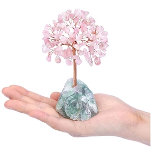 Close-up of a handmade crystal tree with pink quartz leaves and green raw stone base
