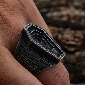 Detailed close-up of vintage punk ring with coffin texture on a natural bark background