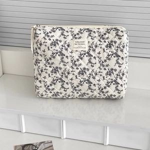 Detail of floral quilted makeup bag with zipper and beige fabric label on cotton fabric