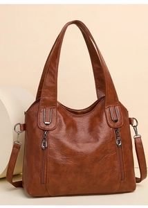 Detail view of brown leather tote bag with metallic zippers and adjustable shoulder strap