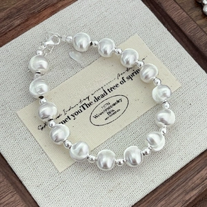 Macro view of minimalist silver beaded cat-eye bracelet with lobster clasp on card