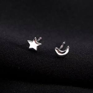 Macro detail of asymmetric S925 sterling silver star and moon stud earrings with mirror finish