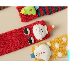 Detail of coral fleece Christmas socks featuring plush Santa, snowman, and tree dolls
