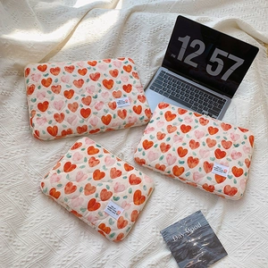 Detailed view of three quilted laptop sleeves with red heart and green leaf patterns