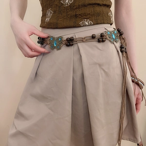 Detailed close-up of woven waist chain with bronze butterflies and blue rhinestones