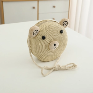 Détail d'un sac bandoulière en paille tressée beige avec oreilles et visage d'ours