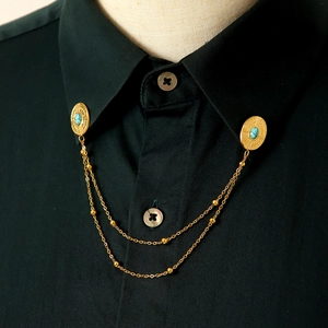 Dettaglio catena per colletto vintage dorata con pietre turchesi su camicia nera