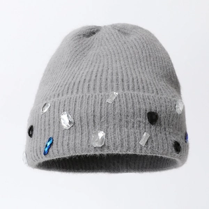 Détail du bonnet en tricot gris orné de strass multicolores sur un tissu duveteux