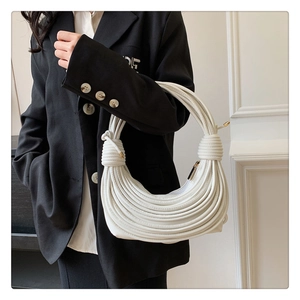 Détail de la texture tressée blanche et ferrures dorées sur le sac bandoulière