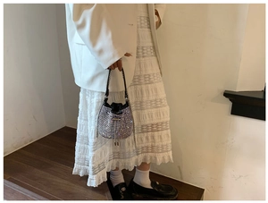 Detail of a black rhinestone drawstring bucket bag with silver chain and fringe tassels