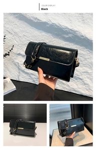 Detail of black glossy crinkled leather bag featuring a sleek gold metal bar closure
