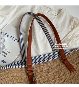 Detail of straw woven tote with brown leather handles and blue striped fabric lining