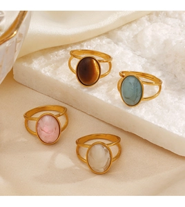 Detail of four gold geometric oval rings with resin cabochons on natural stones