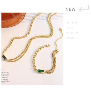 Detail showing gold double-chain necklace and bracelet set with square green gems