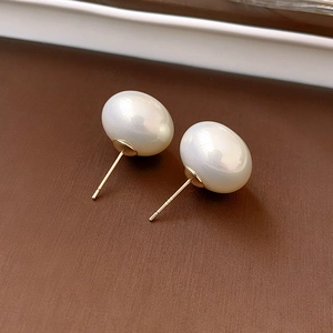 Detailed macro view of white oval pearl stud earrings with elegant gold posts
