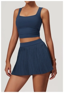 Detail of dark blue tennis set showing ruching on vest and pleated skirt texture