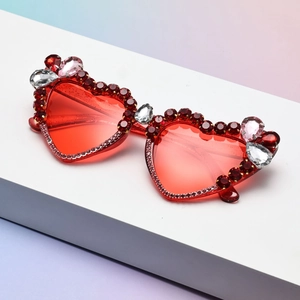 Detailed view of red heart-shaped sunglasses featuring hand-set crystals and rhinestones