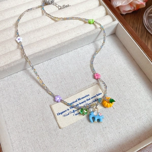 Detailed shot of beaded necklace with elephant and pumpkin charms on jewelry display