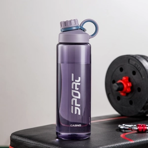 Detailed view of a purple sports water bottle on a gym bench next to dumbbells