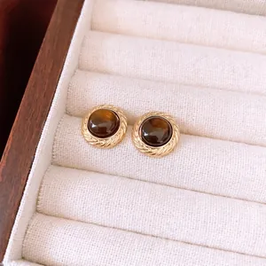 Vintage brown resin round stud earrings with golden textured edge in a jewelry box