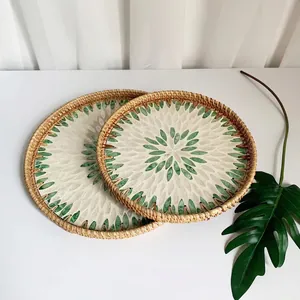 Detail of round woven rattan trays with inlaid green and white seashell leaf patterns