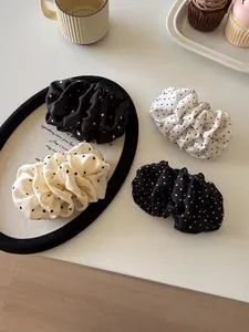 Close-up of four assorted polka dot silk hair scrunchies on a white display plate