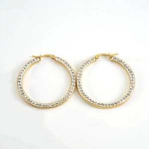 Detailed view of large gold hoop earrings with micro-paved white zircons on white background