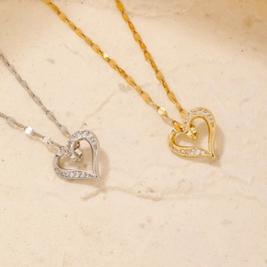 Macro shot of gold and silver heart necklaces with zircon inlay on a stone background