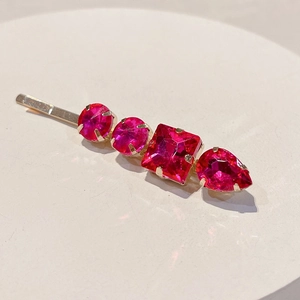 Detail view of pink rhinestone hair clip with geometric crystal shapes on gold metal base