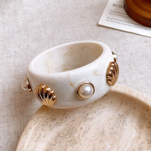 Close-up of cream resin marble bangle with gold shells and pearl embellishments
