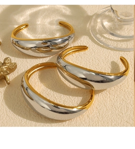 Detail of chunky two-tone gold and silver open cuff bracelet with polished finish