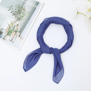 Detail showing a blue chiffon neck scarf tied on a magazine with floral accents