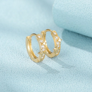 Macro shot of gold hoop earrings with star patterns and sparkling zircon stones