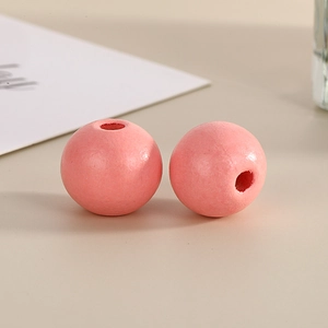 Macro shot of two 16mm round pink painted wood beads for DIY jewelry making and crafts