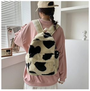Detail of plush faux fur backpack featuring black heart patterns and soft beige texture