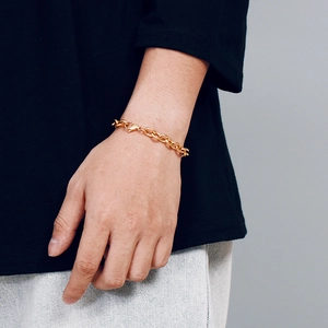 Close-up of a gold-plated stainless steel cross chain bracelet worn on a wrist