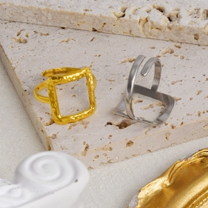 Detail of square hollow geometric open rings in gold and silver on stone